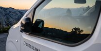 Österreichische Bergwelt gespiegelt im Camper Van Fenster