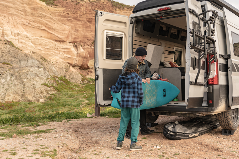 Vater und Sohn laden Surfbretter in Camper Van in Portugal