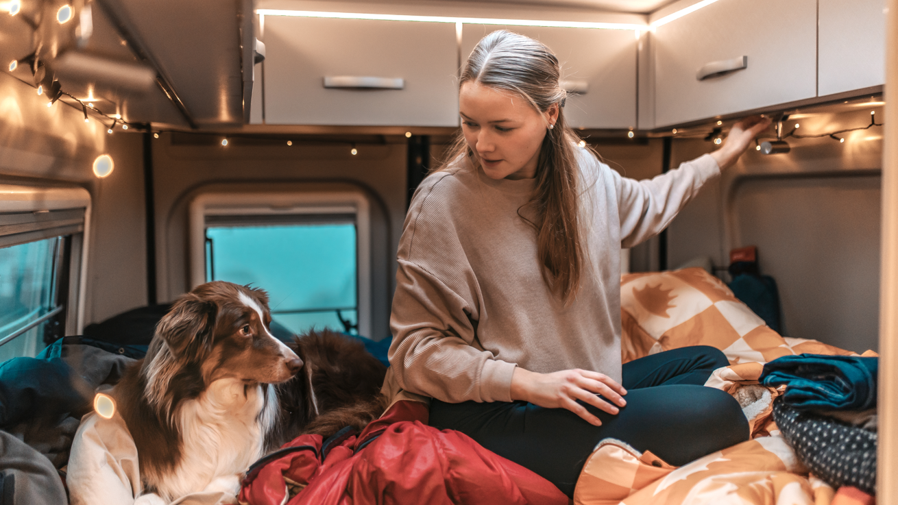 Carly Eck und Hund Malu im Doppekbett des CROSSCAMP 640 Camper Vans