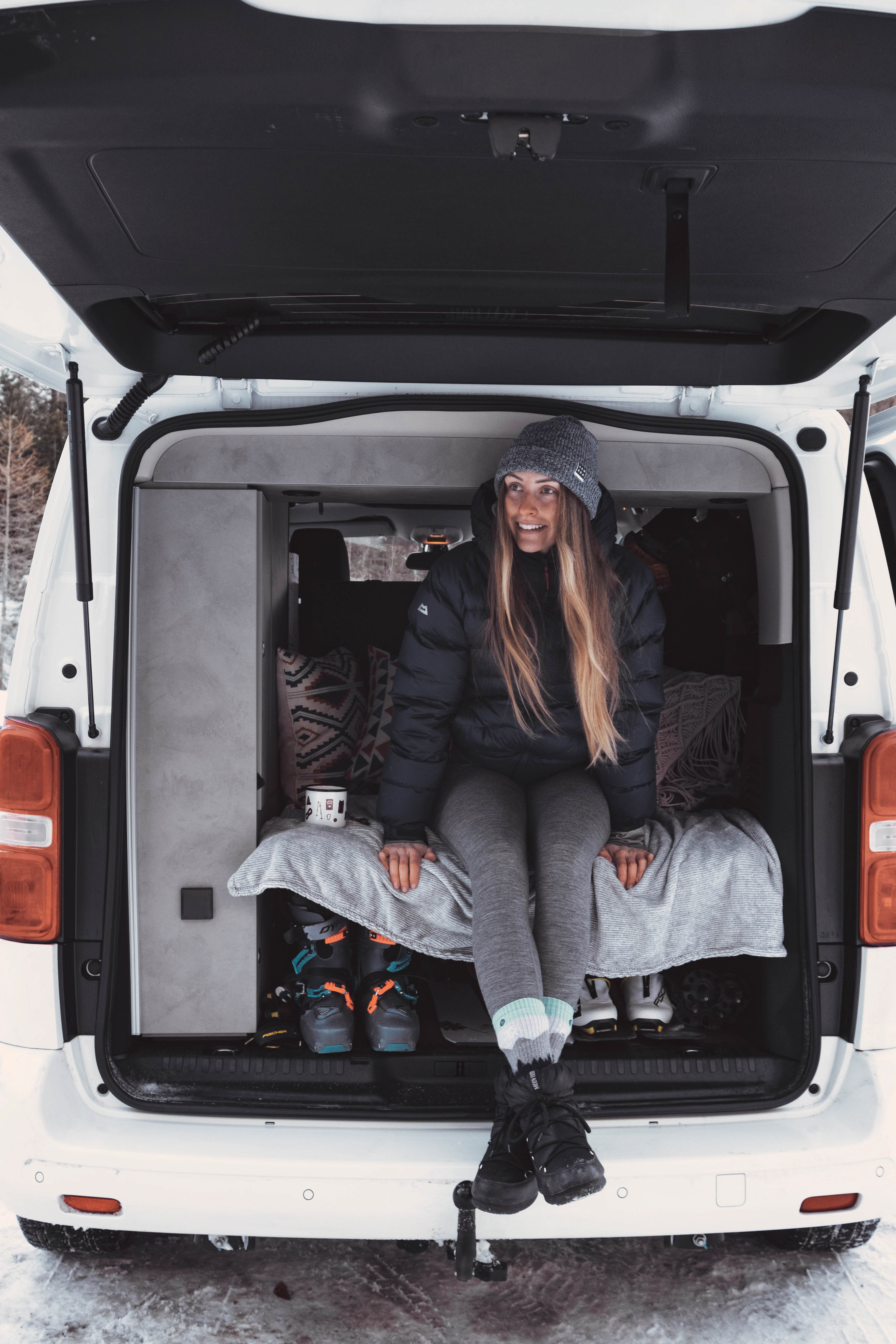 Skimo-Profi Laura sitzt im Heck des gemütlichen CROSSCAMP beim Wintercamping in Kärnten
