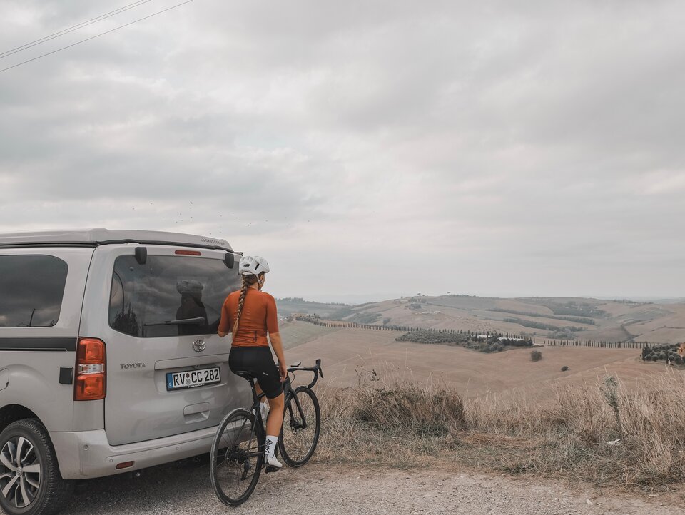 Alina Jäger steht mit ihrem Rennrad in den Dolomiten vor dem CROSSCAMP